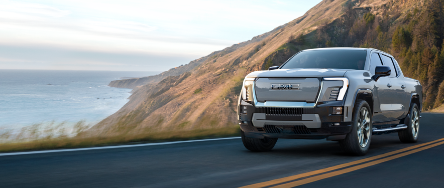 GMC Sierra EV on a coastal road trip at dusk.