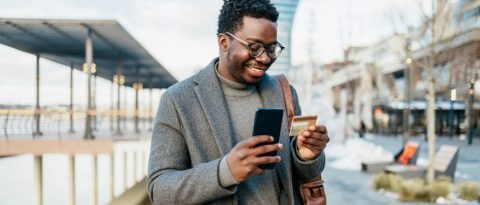Smiling man inputting credit card information into his phone.