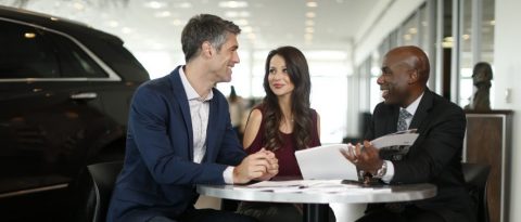 Salesperson and customers discussing auto finance terms at dealership