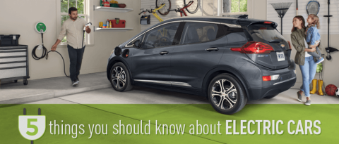 Chevrolet Equinox EV gris estacionado cerca de una playa rocosa.