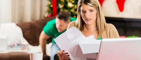 Woman going through bills in front of holiday decorations