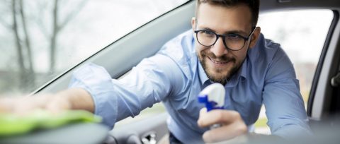 Smiling young man cleaning car interior