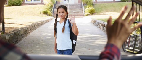 Mother in car dropping off daughter In front of school gates