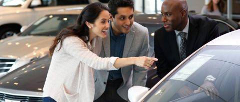 Mujeres sonrientes mirando el Chevrolet Bolt azul en un concesionario.