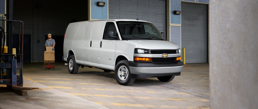 a worker next to a white van using a dolly to move boxes
