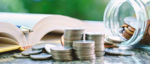 a jar spilling coins out in front of an open book