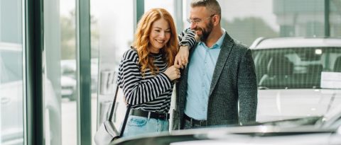 Happy couple looking at vehicles in a GM showroom.