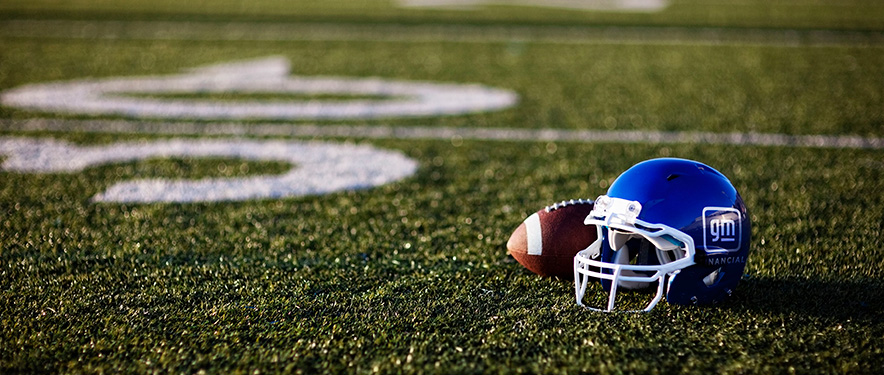Football and blue GM Financial helmet on a football field