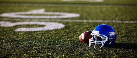 Football and blue GM Financial helmet on a football field