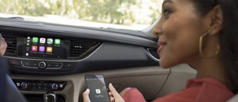 Woman in car accessing CarPlay on smartphone
