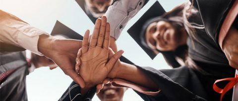 Recent graduates huddled in a circle