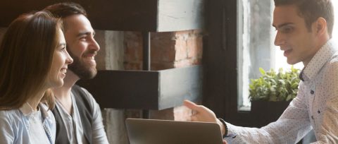 Young married couple reviewing insurance options with a broker.