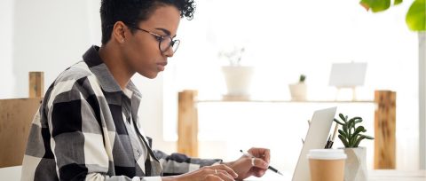 Mujer negra con anteojos usando una computadora portátil