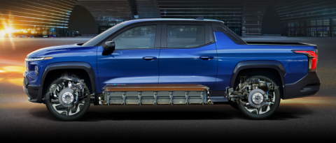 Side view of a blue Chevrolet Silverado RST in front of a futuristic cityscape 
