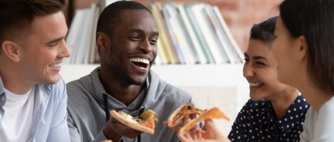 Four diverse people eating slices of pizza