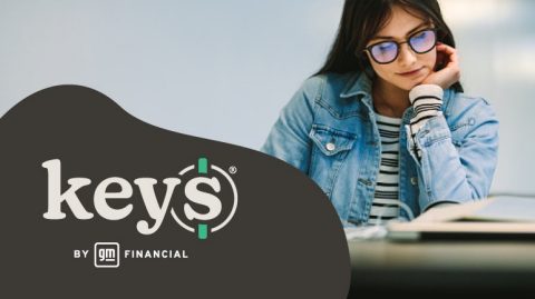 La estudiante mira hacia abajo el libro mientras estudia con el logotipo de KEYS Online superpuesto