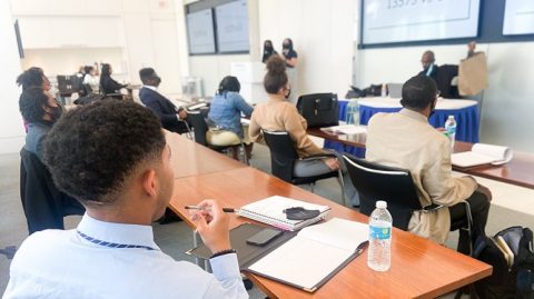 Estudiantes de la Congressional Black Caucus Foundation sentados en escritorios mientras escuchan una presentación en vivo de KEYS