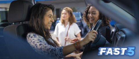 Smiling woman getting ready to drive a new GM vehicle off the lot, with Fast 5 logo overlaid.