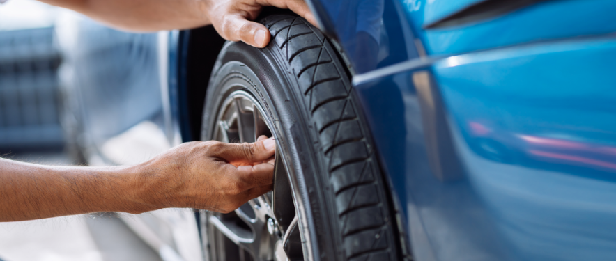 Person preparing to put air in tire of a blue GM car.