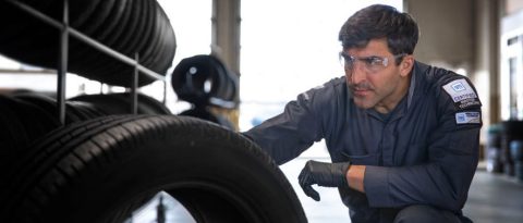 GM Certified Service technician inspecting tires in a garage.