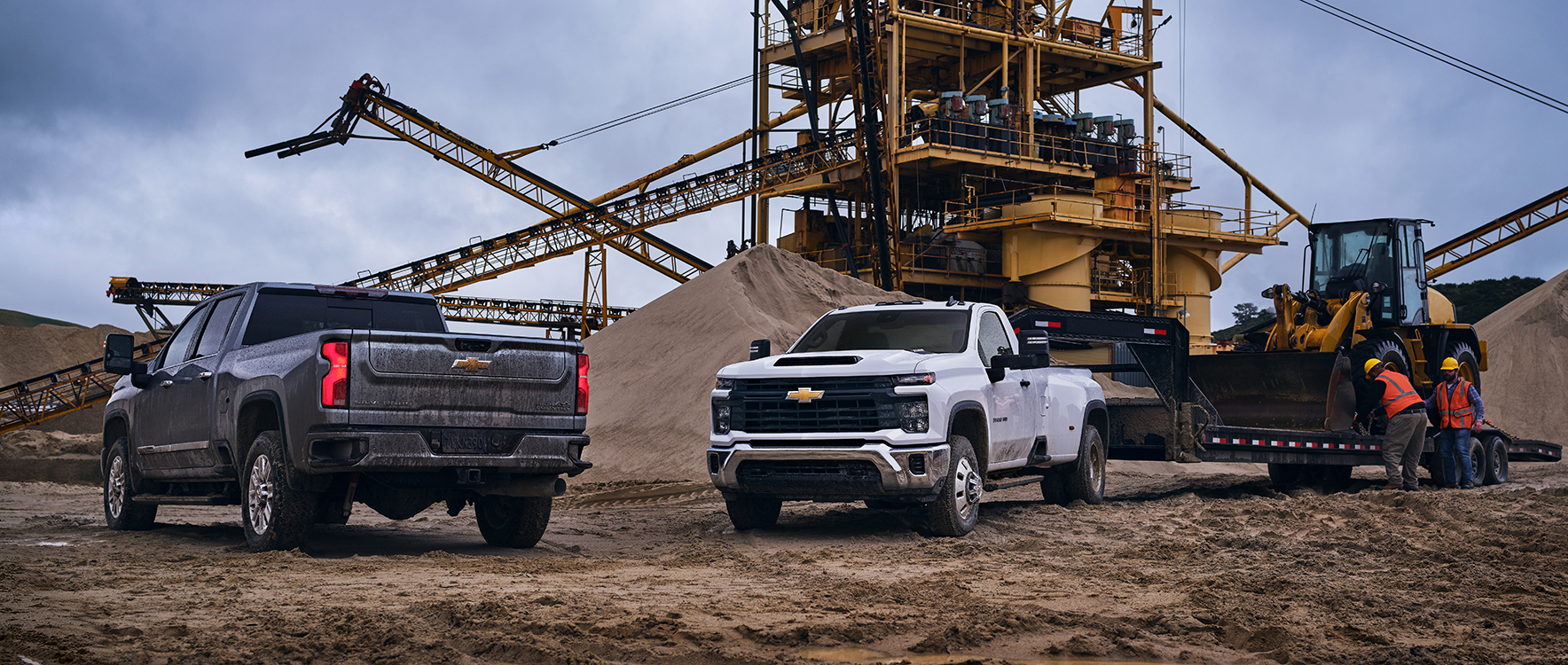 Two GM trucks at a construction site.